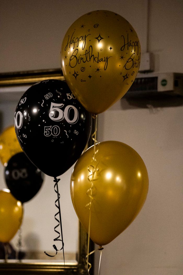 gallery-03 Elegant black and gold balloons celebrate a milestone 50th birthday indoors.